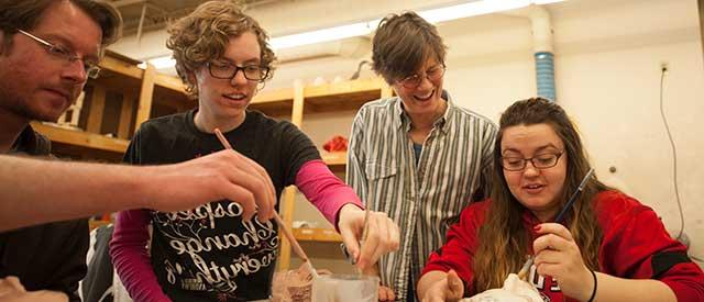 students working with professor on their sculptures