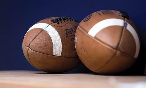 two footballs on a shelf